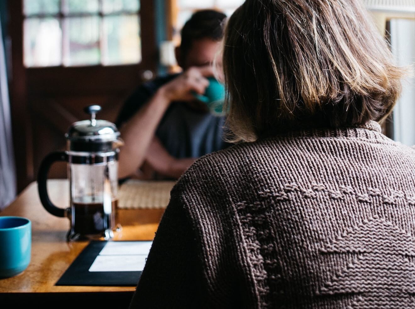 Young woman and man drinking coffee in cabin