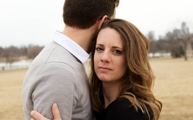 woman embracing male partner staring blankly toward camera