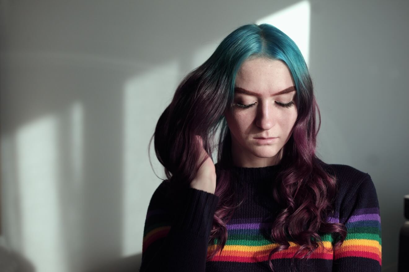 Woman in rainbow sweater playing with her multi-colored hair