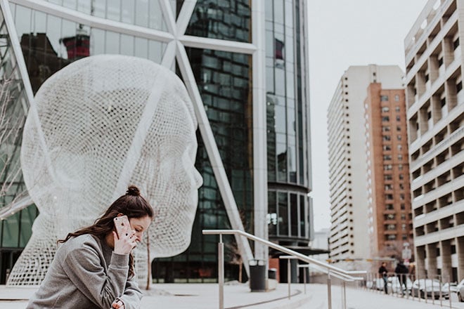 Woman sitting next to sculpture on the phone