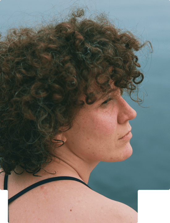 Side profile of a woman with curly hair looking up and to the right