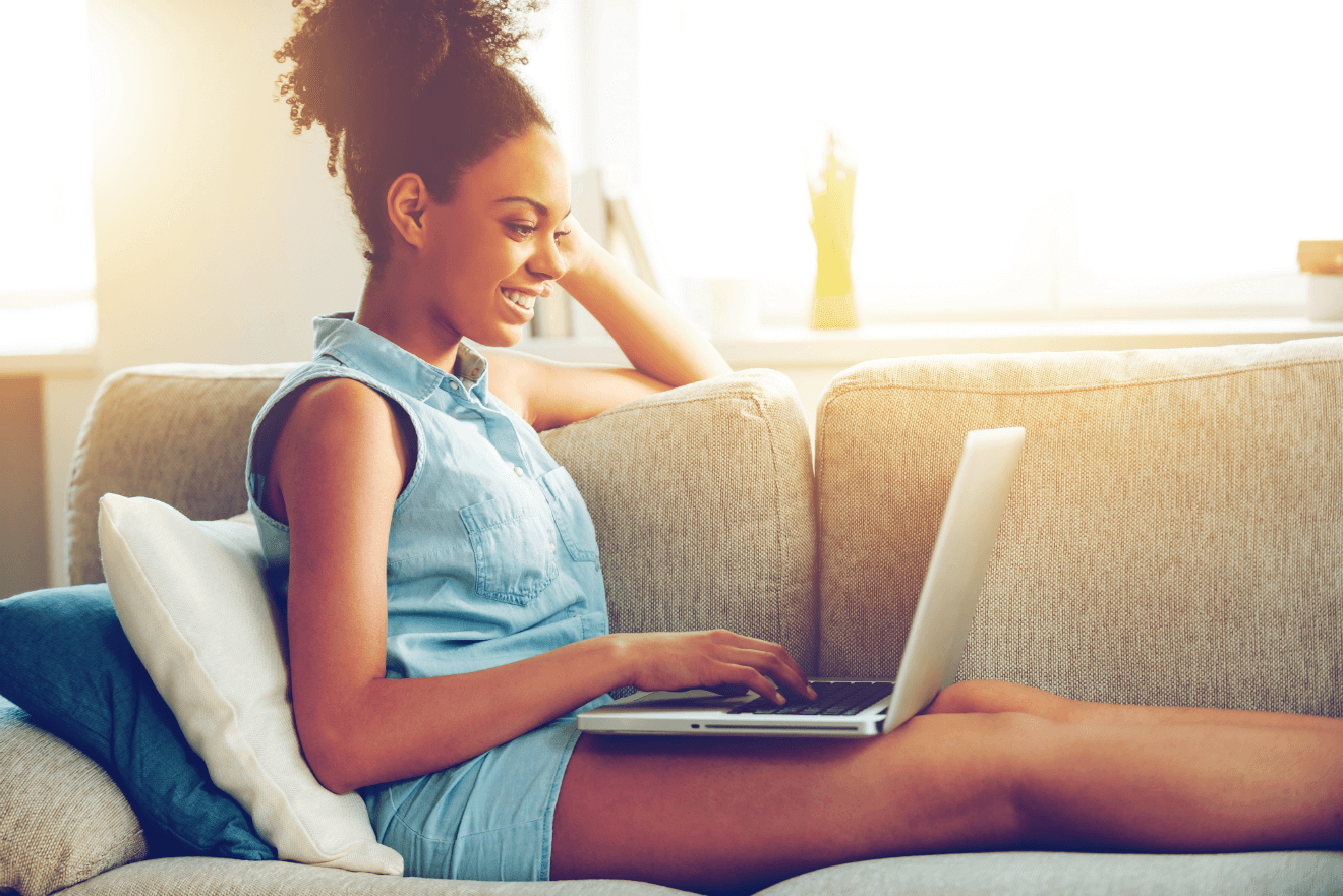 happy woman with laptop lying on couch